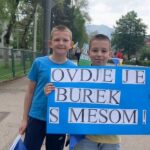“Këtu ka burek me mish!” – disa fëmijë janë bërë viralë me pankartat e tyre kreative gjatë një gare në Bosnjë